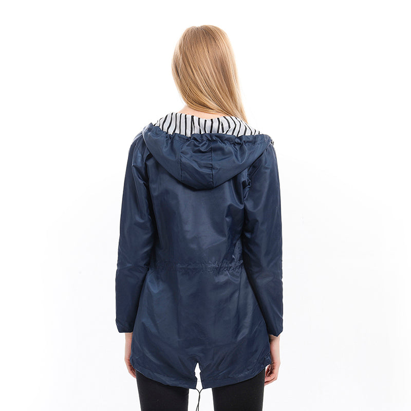 Woman wearing the all-season waterproof rain jacket in an outdoor setting, showcasing its lightweight and breathable design.
