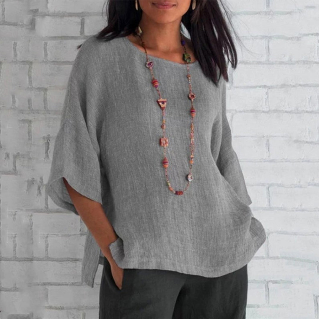 Woman wearing a loose-fitting, 3/4 sleeve linen top.